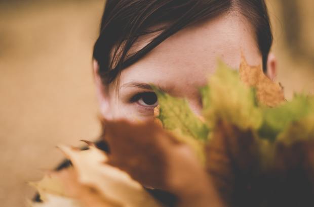 a girl hiding her face behind leaves