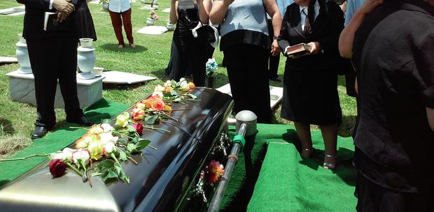 people standing around a casket at a funeral