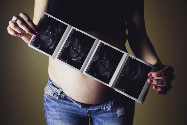 a pregnant woman displaying her sonogram photos