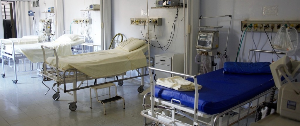 Row of blue and white hospital beds in a hospital room.