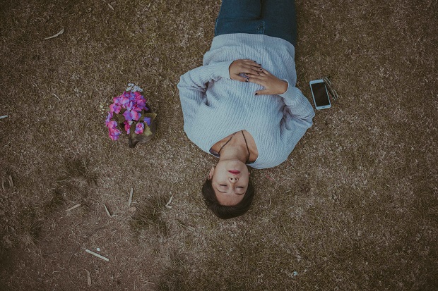 a woman lying on the ground next to a cellphone and bouquet of flowers