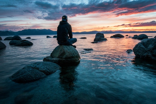a man sitting on a stone on the coast